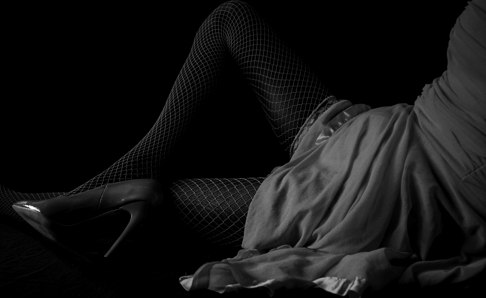 See-through lingerie set paired with fishnet stockings and high heels, featuring sheer fabrics, bold styling, and a seductive, provocative look.